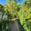 Weg zum Eingang - Geräumige Parterre-Eigentumswohnung mit eigenem Grundstück und Parkflächen in ruhiger Ortsrandlage